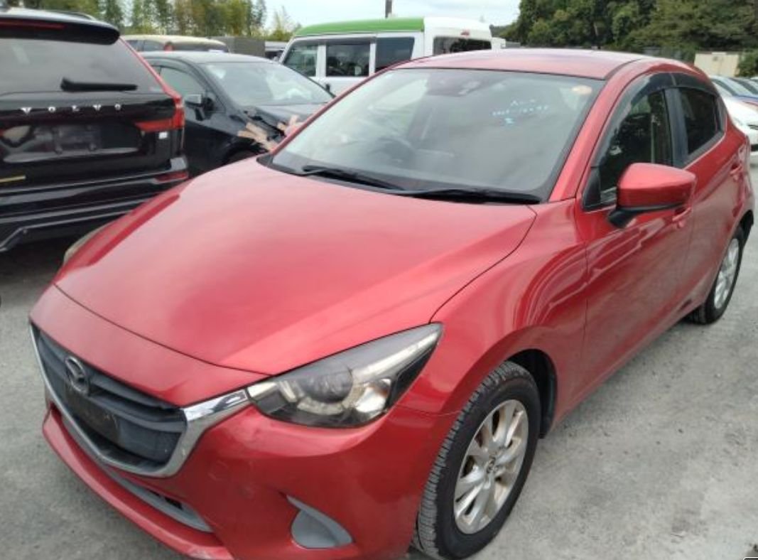 Red Mazda Demio seen from the front left