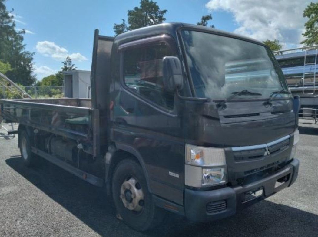 Grey Mitsubishi Fuso Canter flat-deck truck seen from the front right