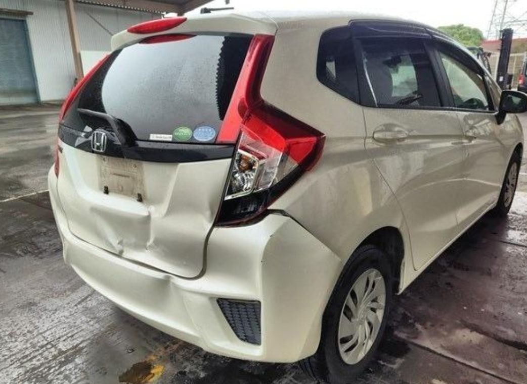 Rear right of the Honda Fit showing a dented tailgate and rear bumper